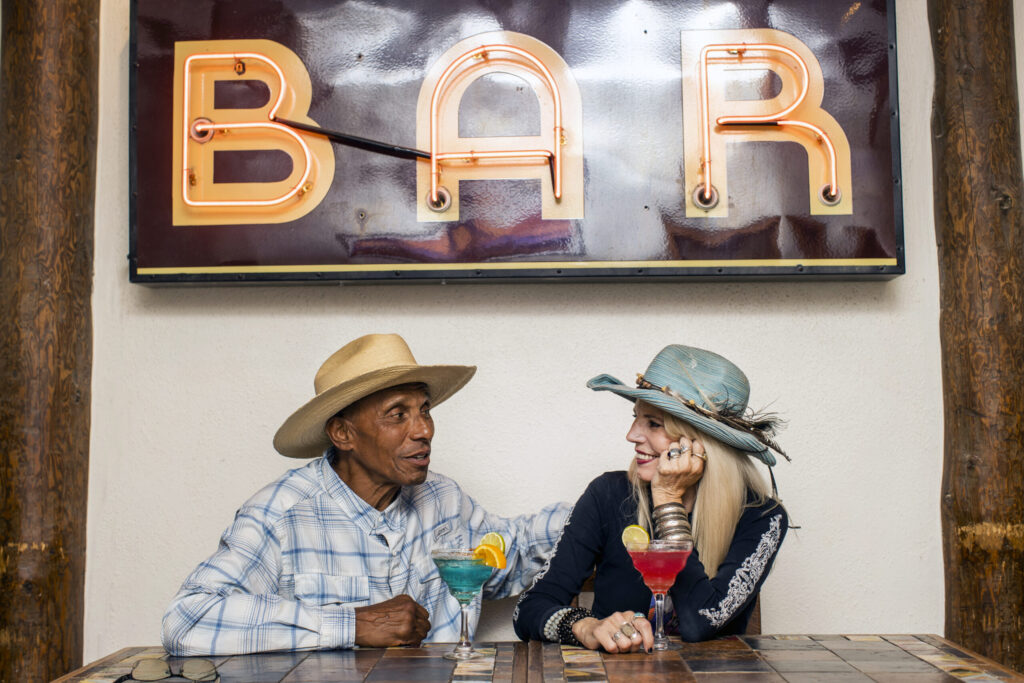 Friends share drinks under neon sign in Adobe Bar