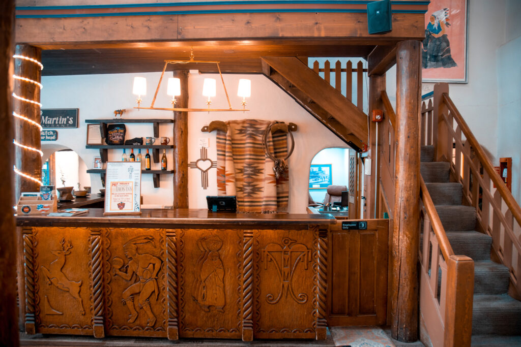 Carved wood reception desk and stairs at Taos Inn