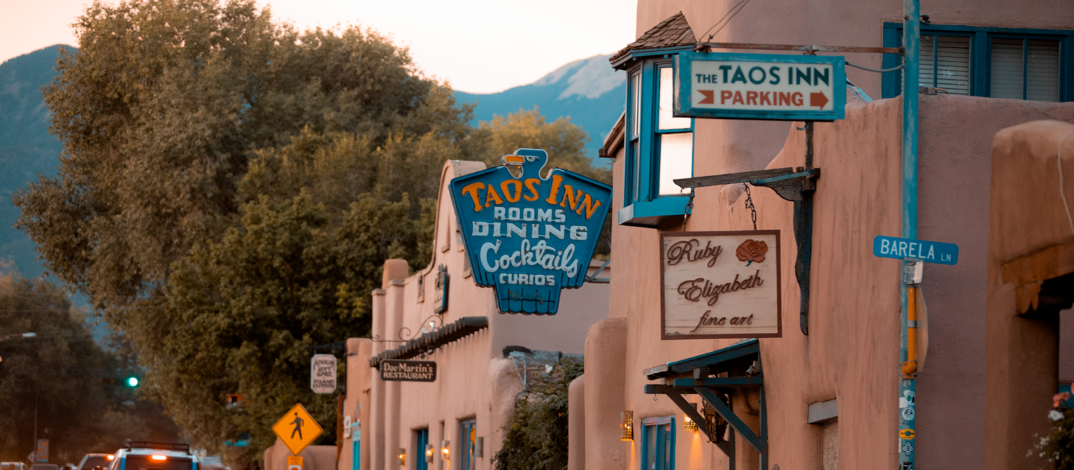 Street view of adobe buildings and signs at dusk