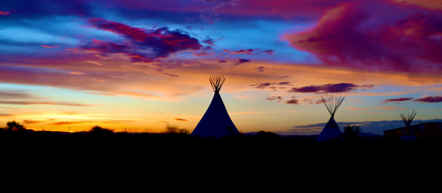 Colorful sunset with silhouettes of teepees