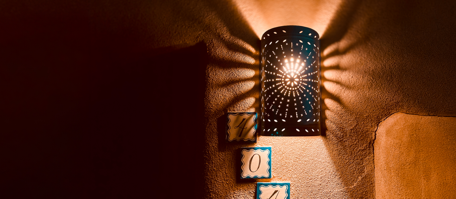 Wall lamp making patterns across the adobe with room number tiles