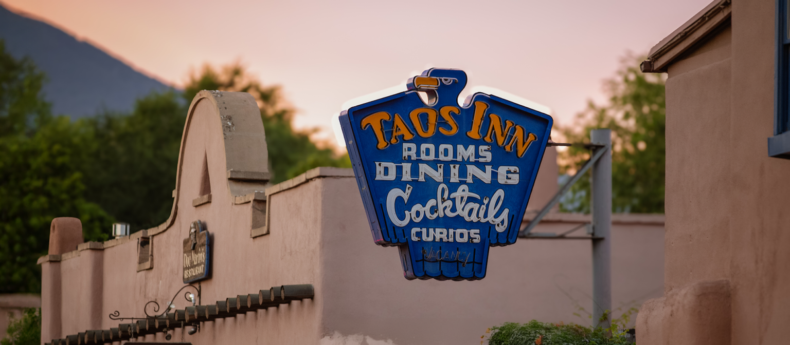 Taos Inn blue thunderbird sign on adobe building at dusk