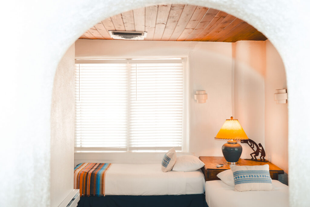 Two twin beds in room corner with lamp