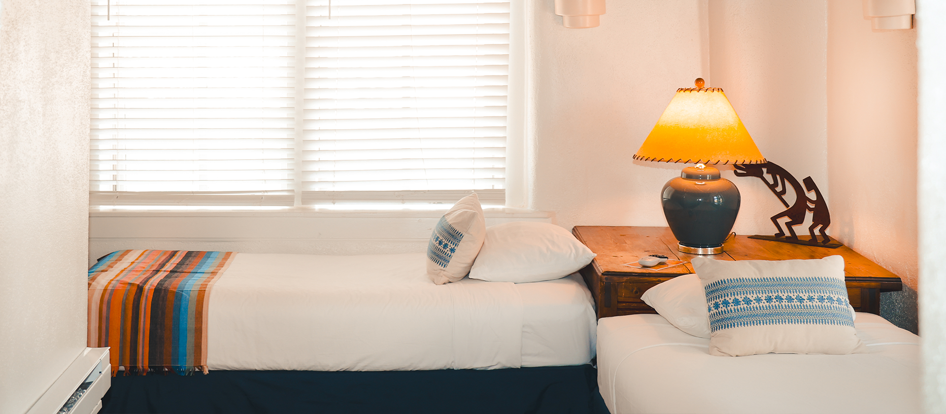 Two twin beds in room corner with lamp