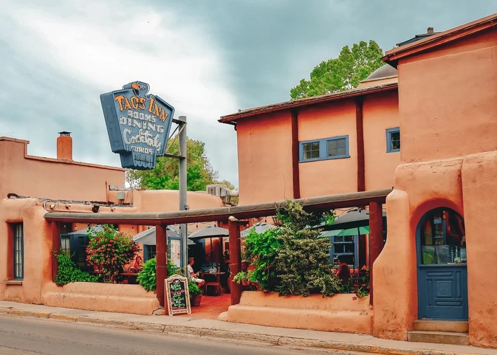 Exterior of Taos Inn with sign and patio