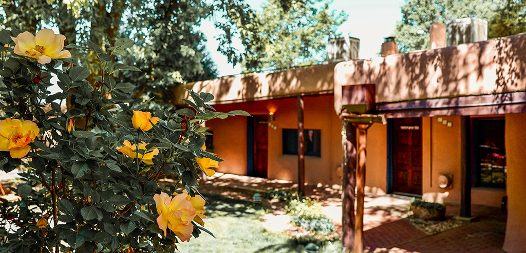 Taos Inn adobe building exterior with rose bushes