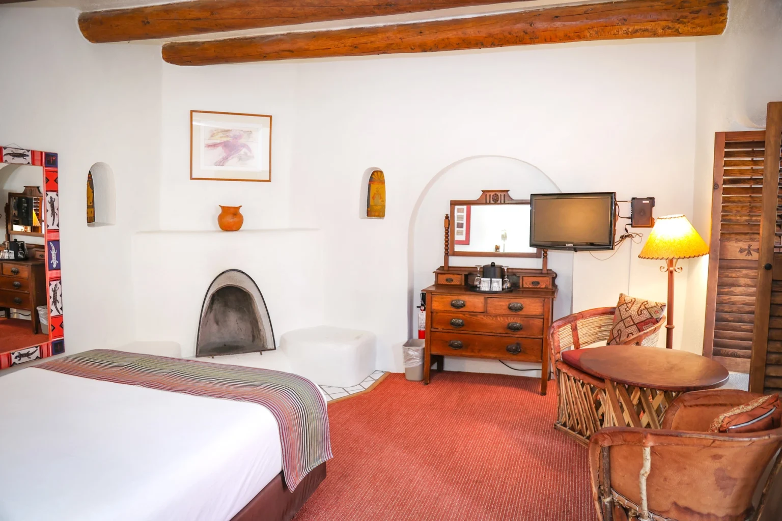 Bed, fireplace, seating area, television, and dresser in standard queen room