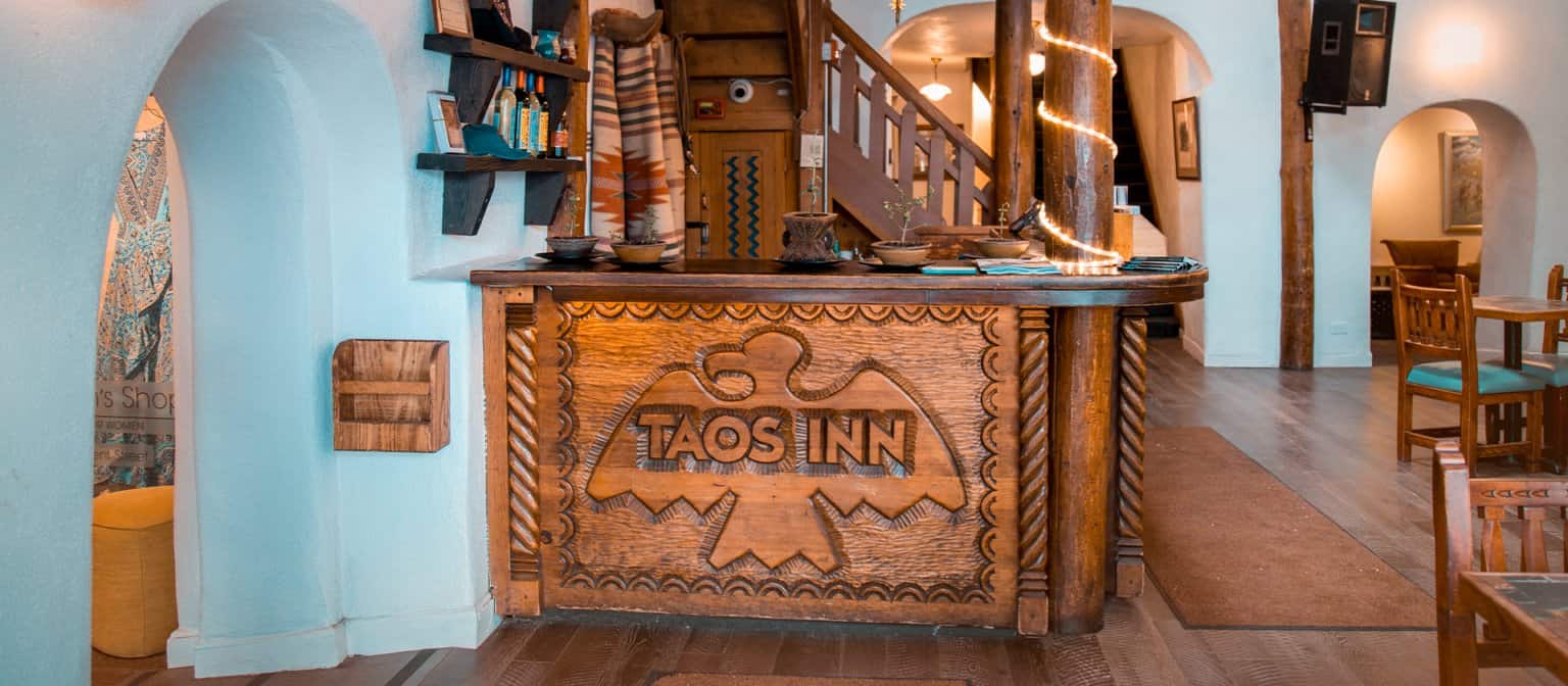 Carved wood reception desk and stairs at Taos Inn