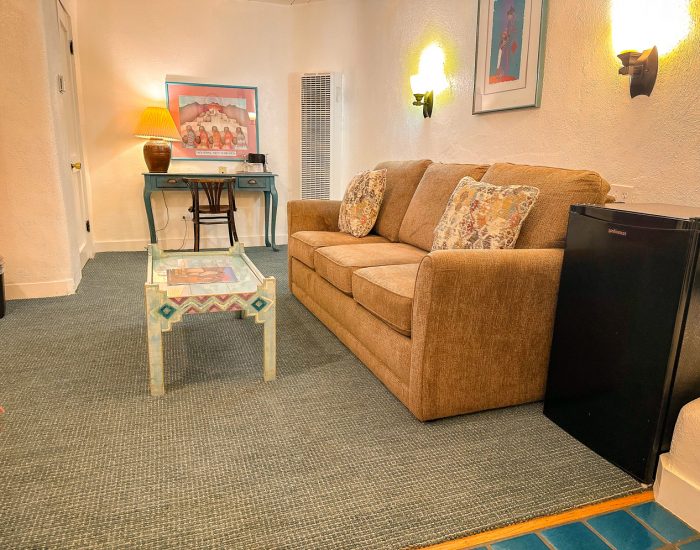 Seating area, desk, and refrigerator in deluxe king room