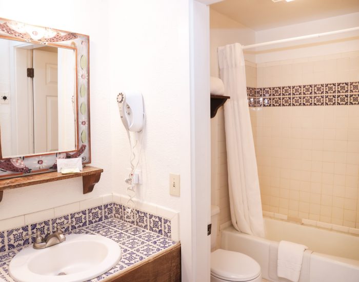 Bathroom sink, vanity, toilet, and tub in standard queen room