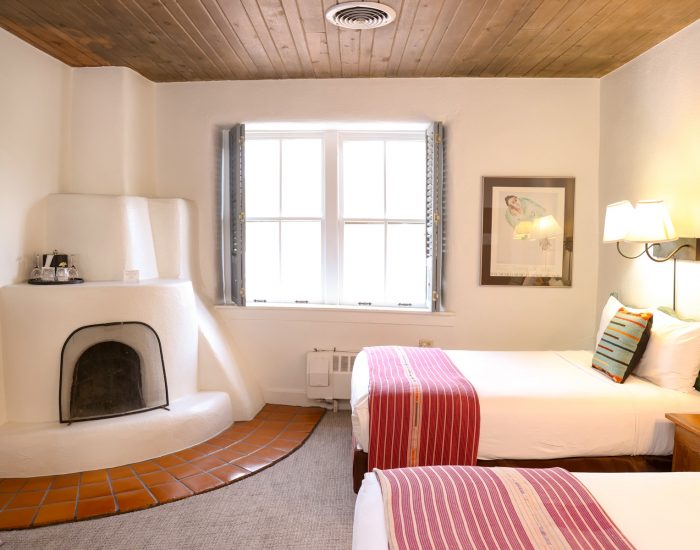 Two full beds in room with fireplace